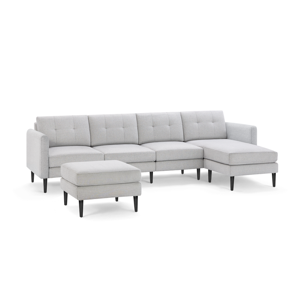 Light gray modern sectional sofa with tufted back cushions, black tapered legs, and matching ottoman on plain background.