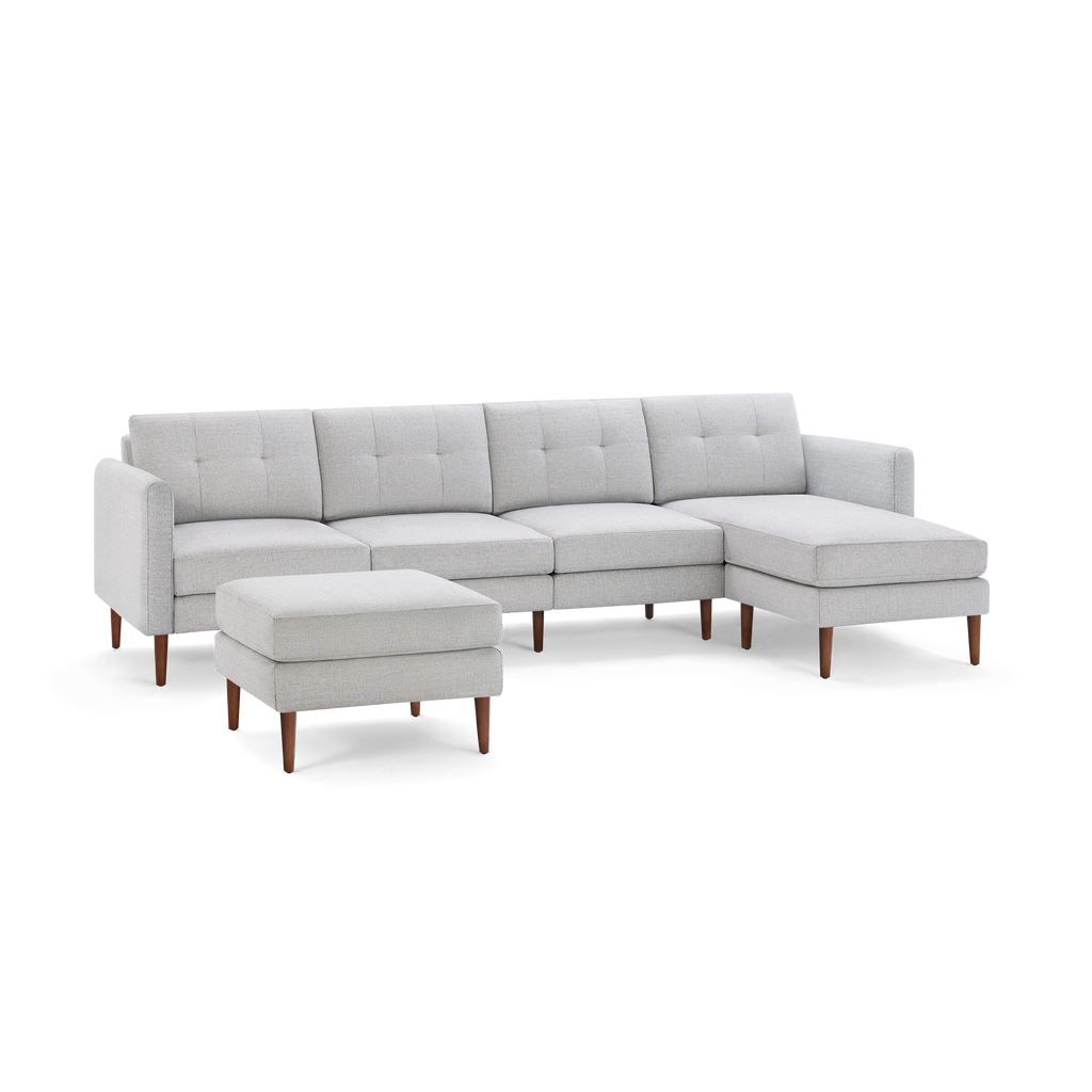 Light gray modern sectional sofa with tufted cushions, wooden legs, and a matching rectangular ottoman on black background.