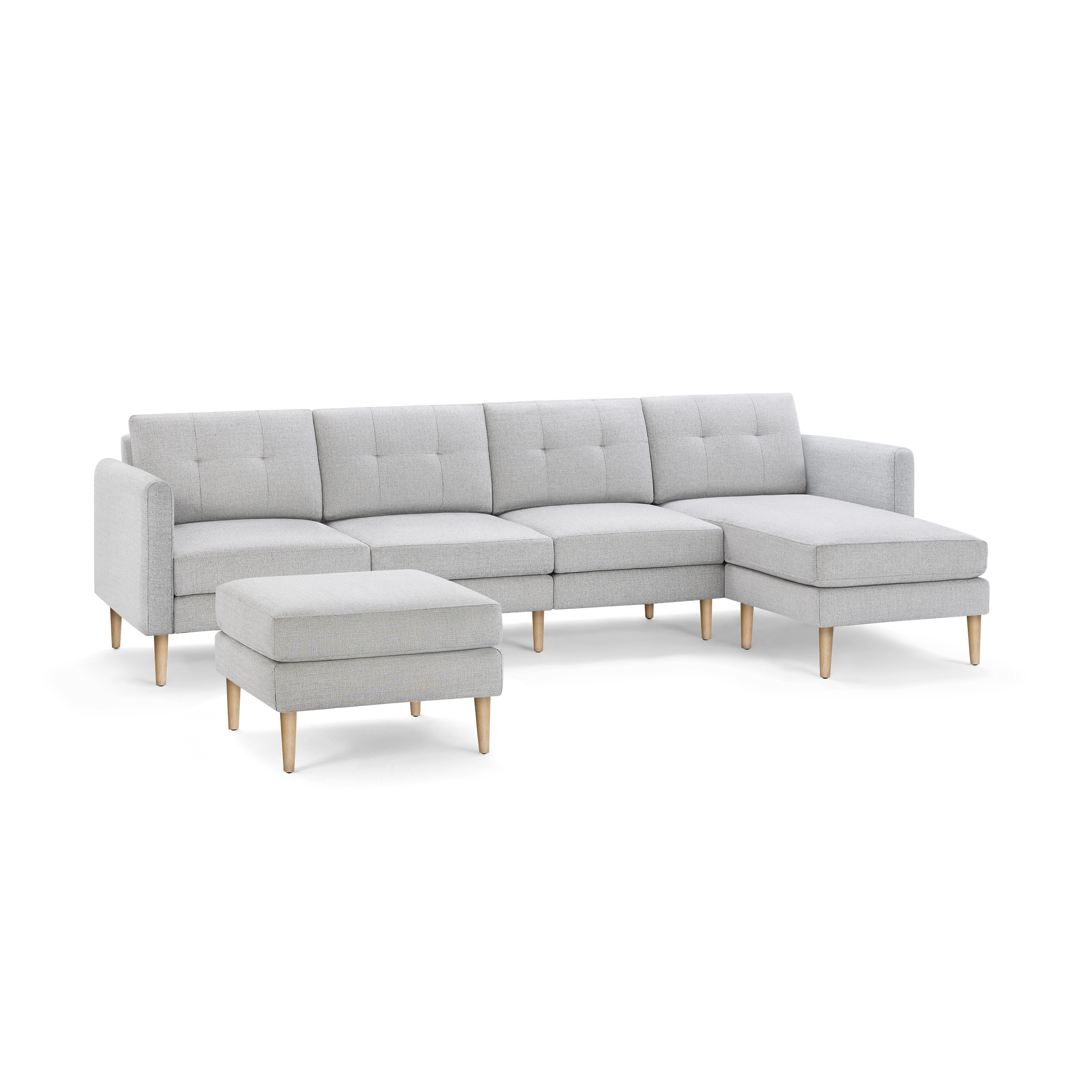 Light gray fabric sectional sofa with tufted cushions, wooden legs, and a matching ottoman, isolated on black background.