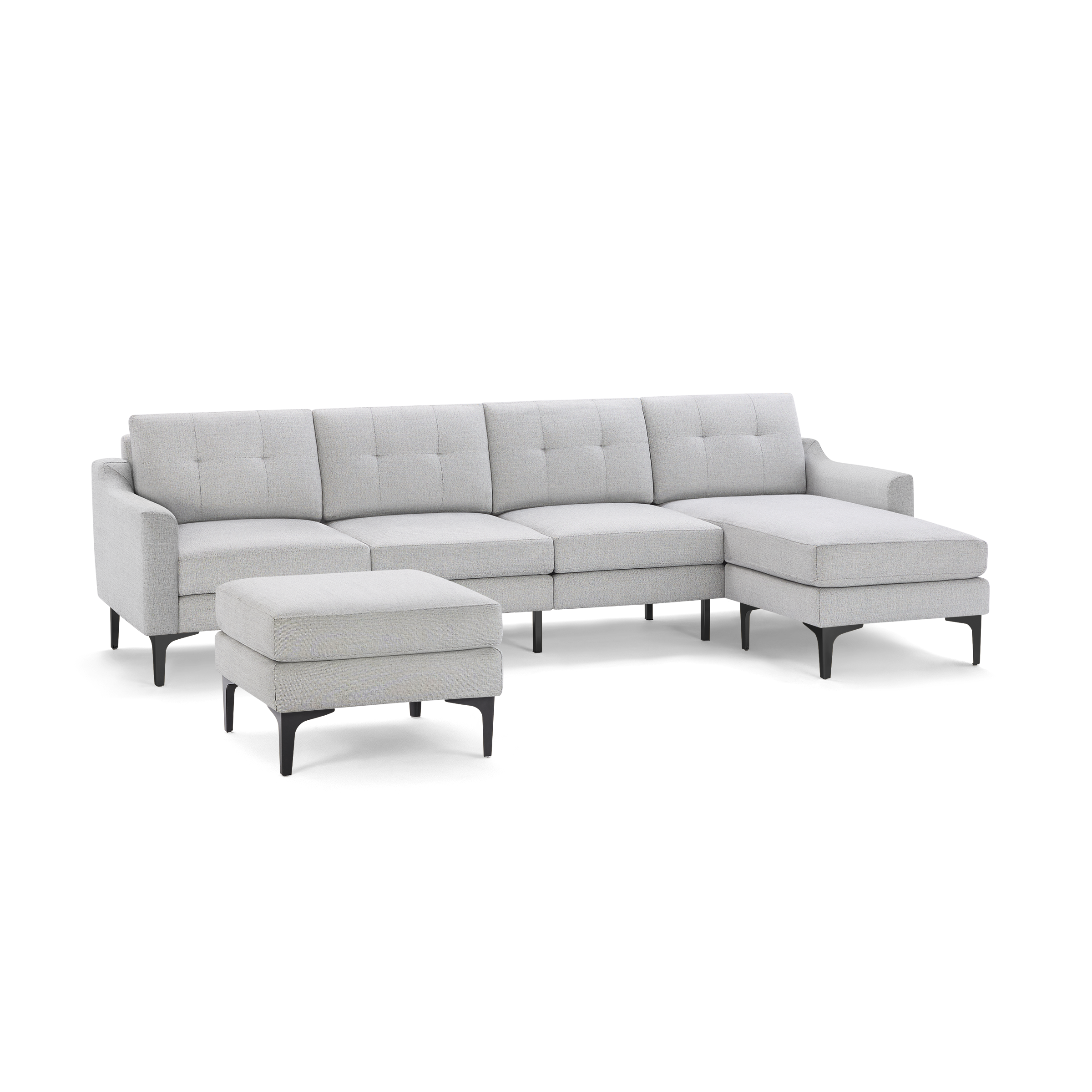 Light gray sectional sofa with tufted cushions, chaise lounge on the right, and matching ottoman with black legs.