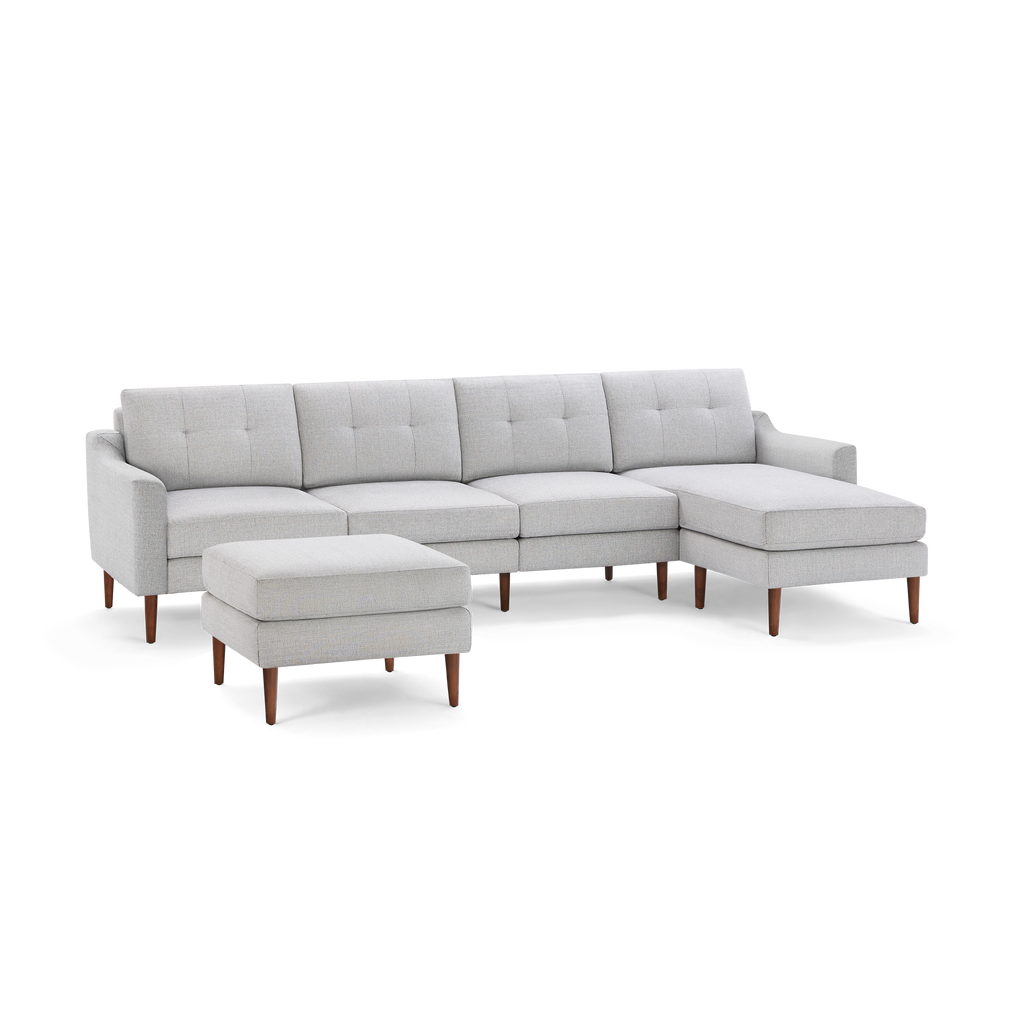 Light gray modern sectional sofa with tufted back cushions, wooden legs, and matching ottoman on a black background.