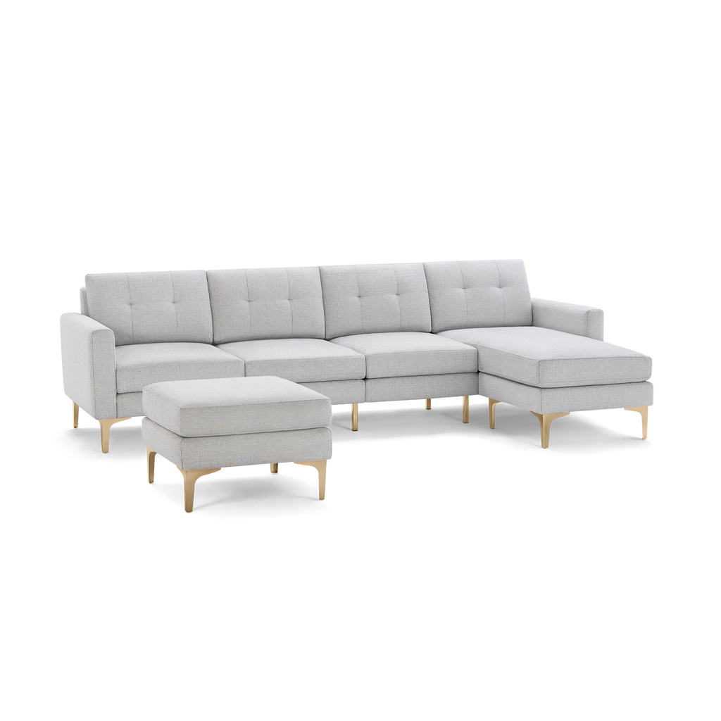 Light gray fabric sectional sofa with tufted back cushions, chaise lounge on the right, and matching ottoman with gold metal legs.