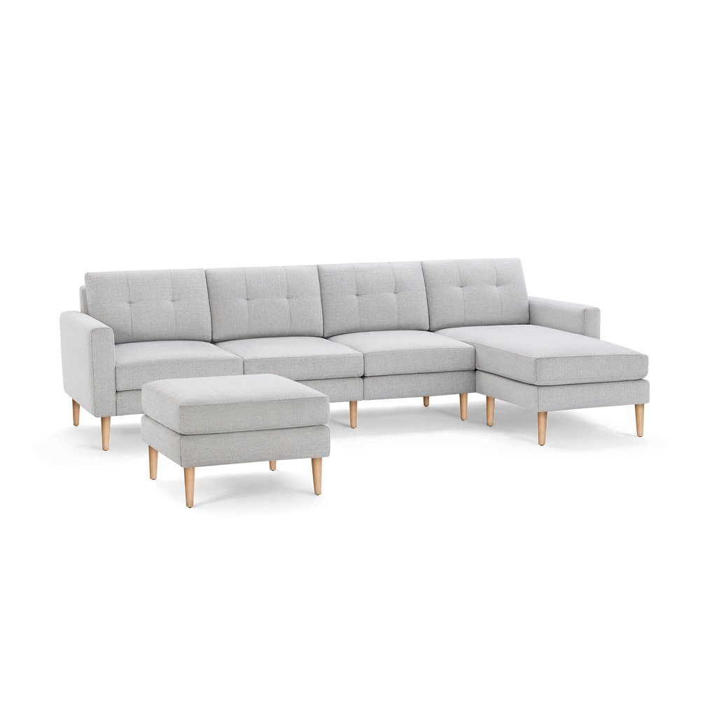 Light gray sectional sofa with tufted cushions, wooden legs, and a matching square ottoman, modern minimalist design.