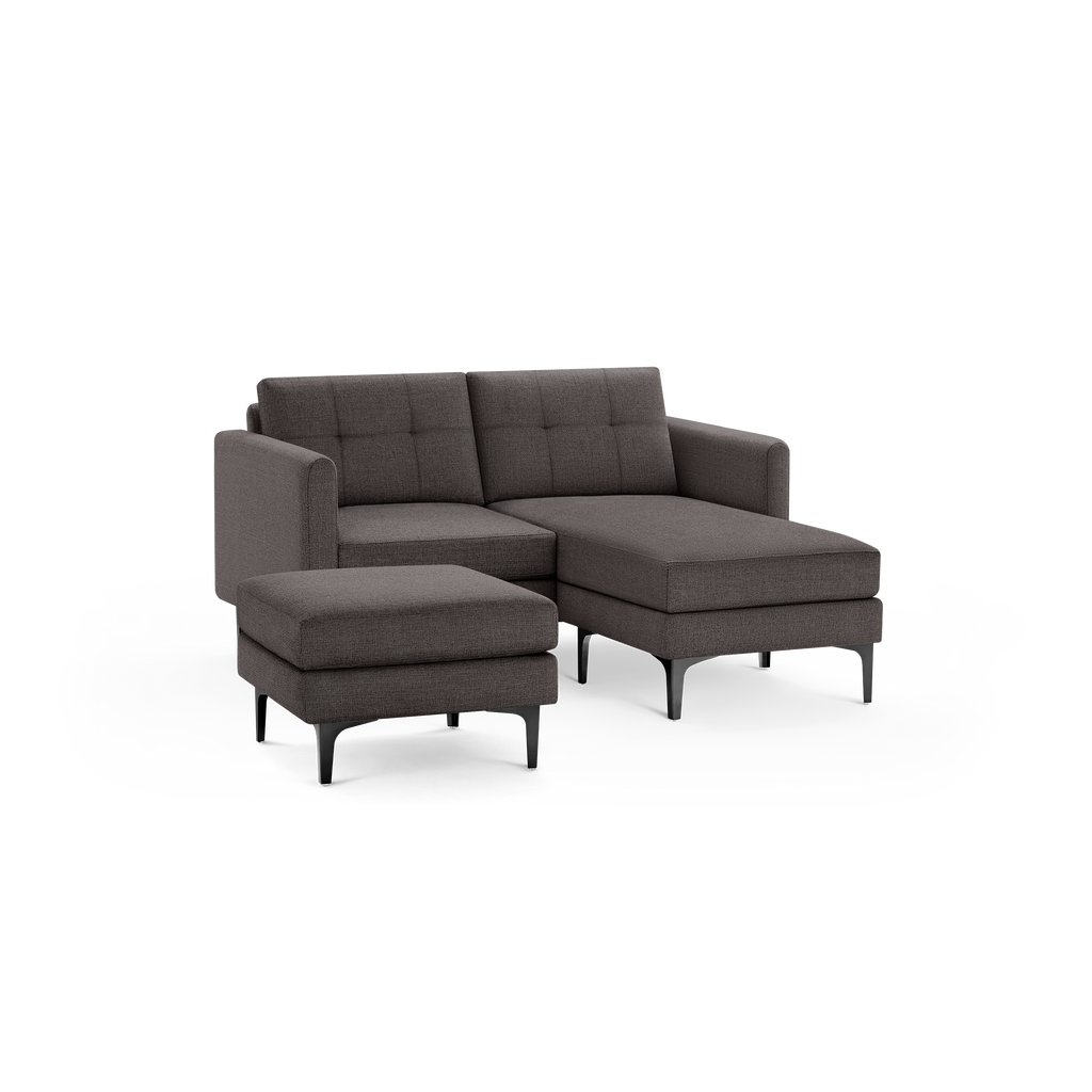 Modern dark gray fabric sectional sofa with tufted back cushions, armrests, and matching ottoman, supported by black metal legs.