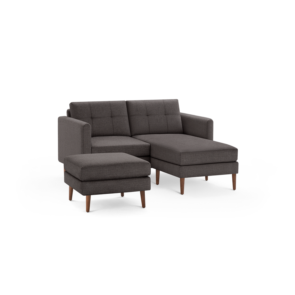 Dark gray fabric sectional sofa with tufted back cushions, wooden legs, and a matching ottoman.