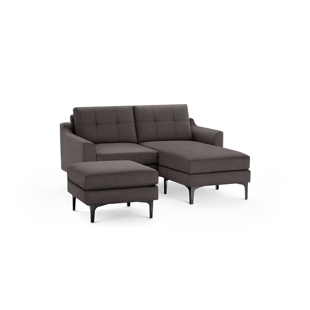 Dark gray modern sectional sofa with tufted back cushions, chaise lounge, and matching ottoman on black legs.