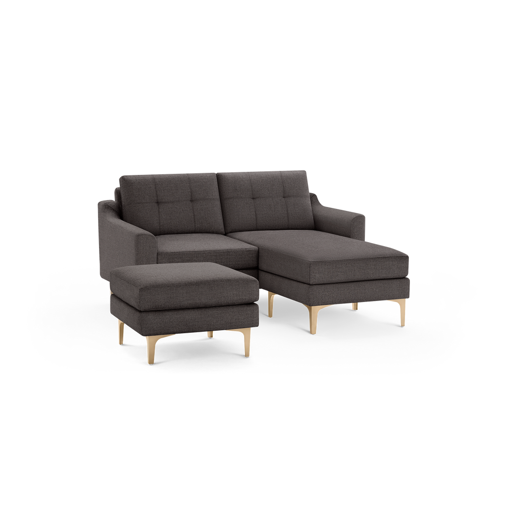 Dark gray fabric sectional sofa with tufted back cushions, wooden angled legs, and a matching ottoman.