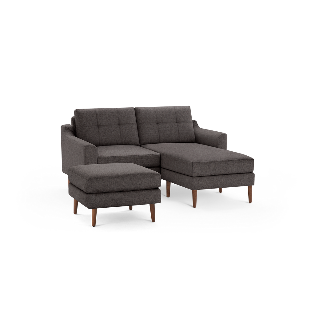 Dark gray mid-century style sectional sofa with tufted back cushions and matching ottoman, supported by wooden legs.