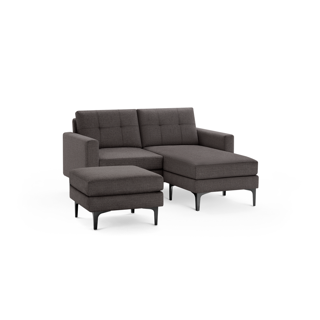 Modern dark gray fabric sectional sofa with a matching ottoman, featuring tufted back cushions and black metal legs.