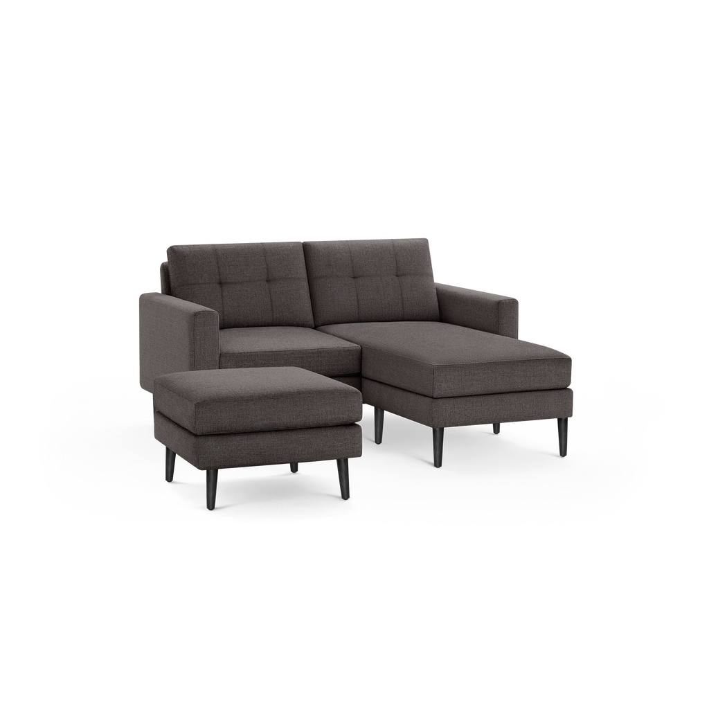 Dark gray fabric sectional sofa with tufted back cushions, featuring a chaise lounge on the right side and a matching ottoman.