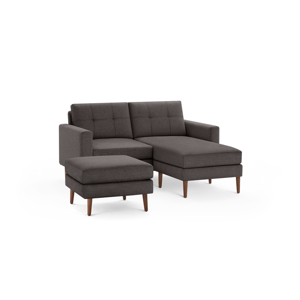 Dark gray fabric sectional sofa with tufted back cushions, wooden legs, and a matching ottoman.
