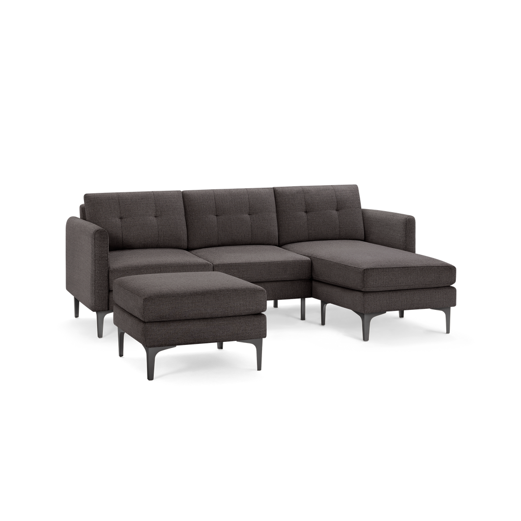 Dark gray fabric sectional sofa with an attached chaise lounge and a separate ottoman, supported by black metal legs.