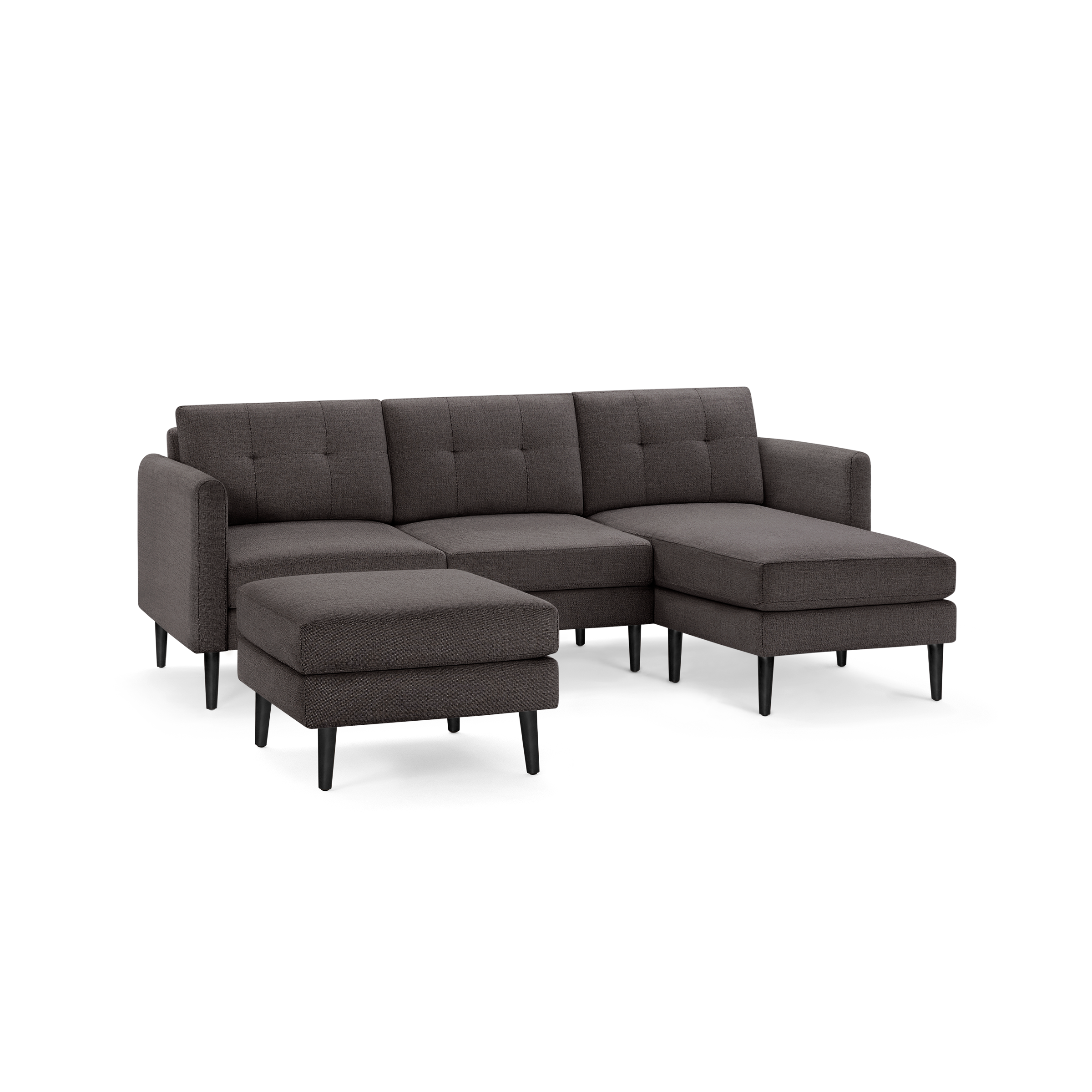 Dark gray modern sectional sofa with tufted back cushions, wooden legs, and matching ottoman on isolated background.