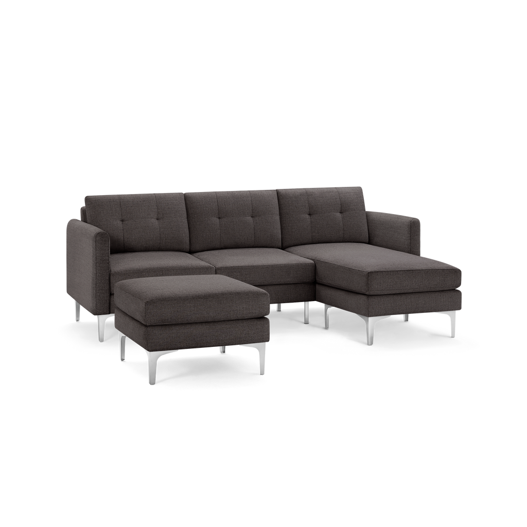 Modern dark gray fabric sectional sofa with tufted cushions, metal legs, and a matching ottoman.