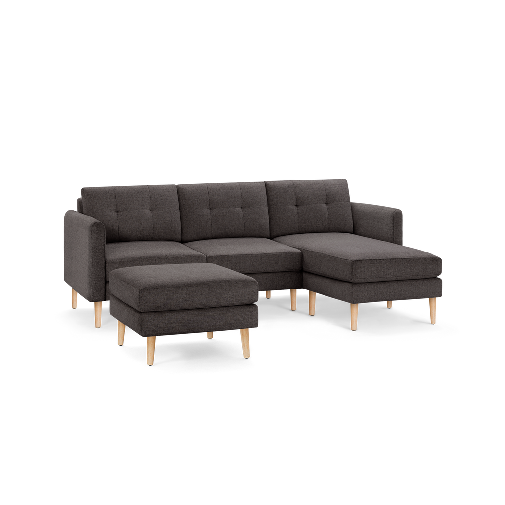 Modern dark gray fabric sectional sofa with tufted cushions, wooden legs, and a matching ottoman.