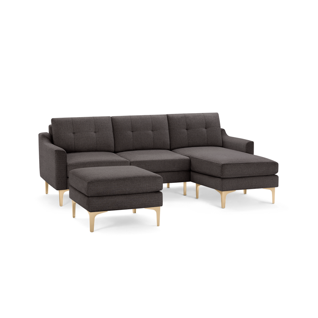 Dark gray sectional sofa with tufted cushions and light wooden legs, including a matching ottoman.