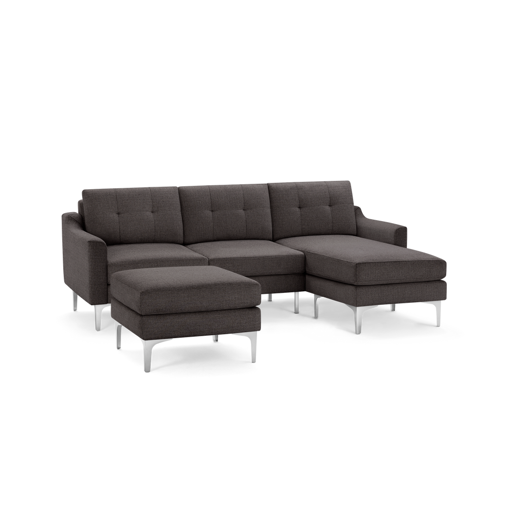 Dark gray fabric sectional sofa with tufted cushions, metal legs, and an ottoman, modern and minimalist design.
