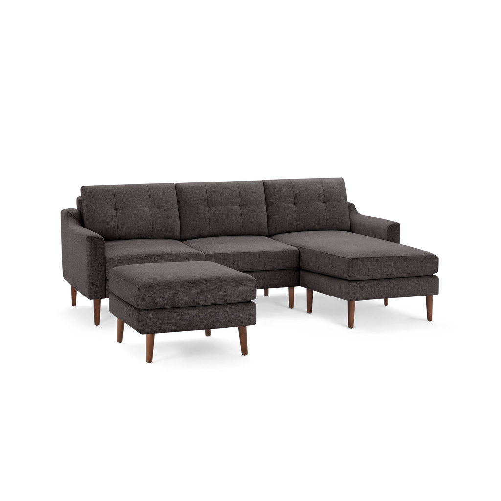 Dark gray fabric sectional sofa with tufted back cushions and wooden legs, including a matching ottoman.