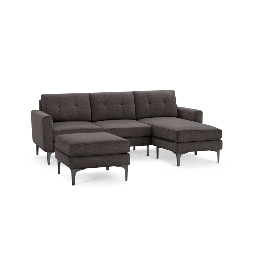 Modern dark gray fabric sectional sofa with tufted back cushions, metal legs, and a matching ottoman.