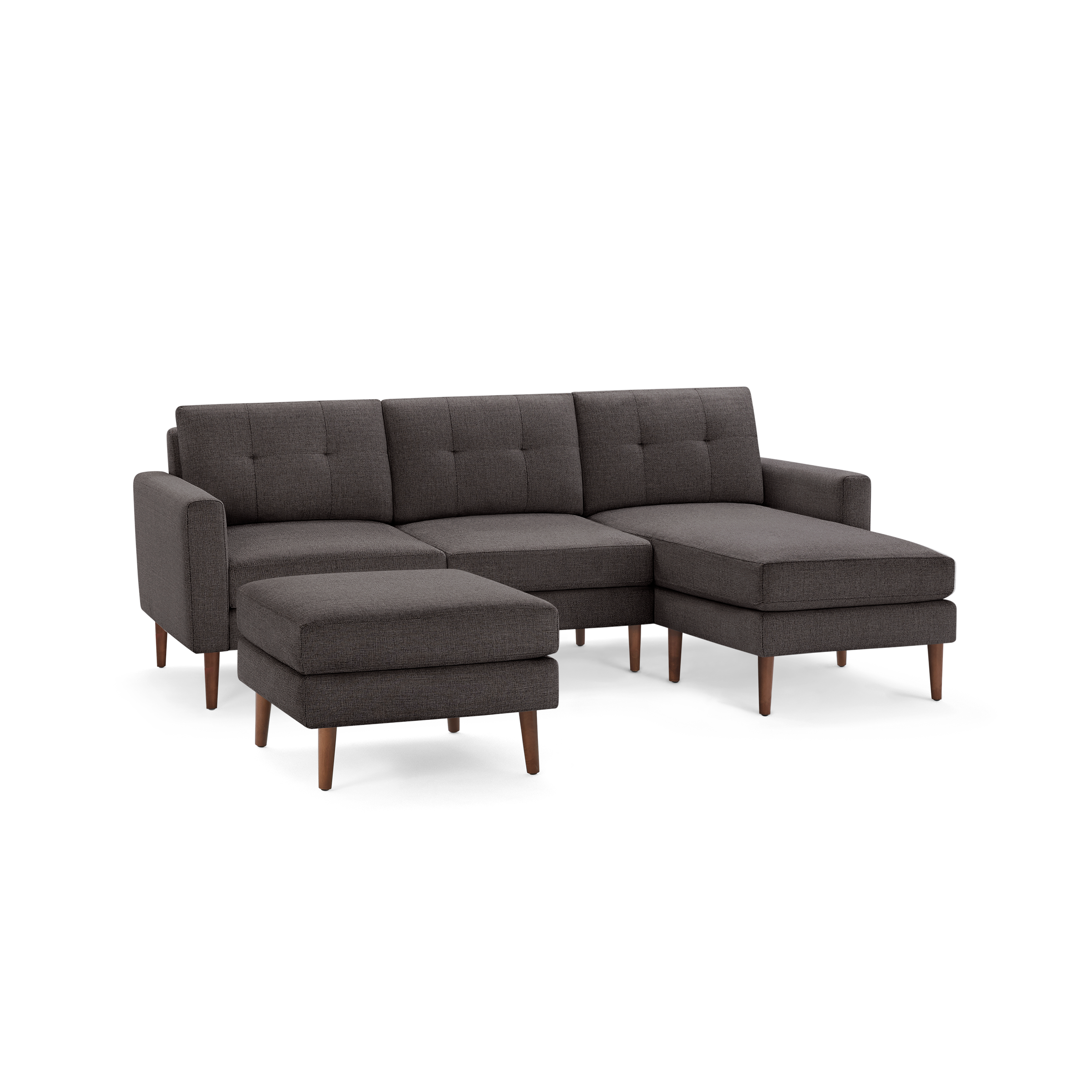 Dark gray upholstered sectional sofa with tufted cushions, wooden legs, and matching ottoman, modern design.