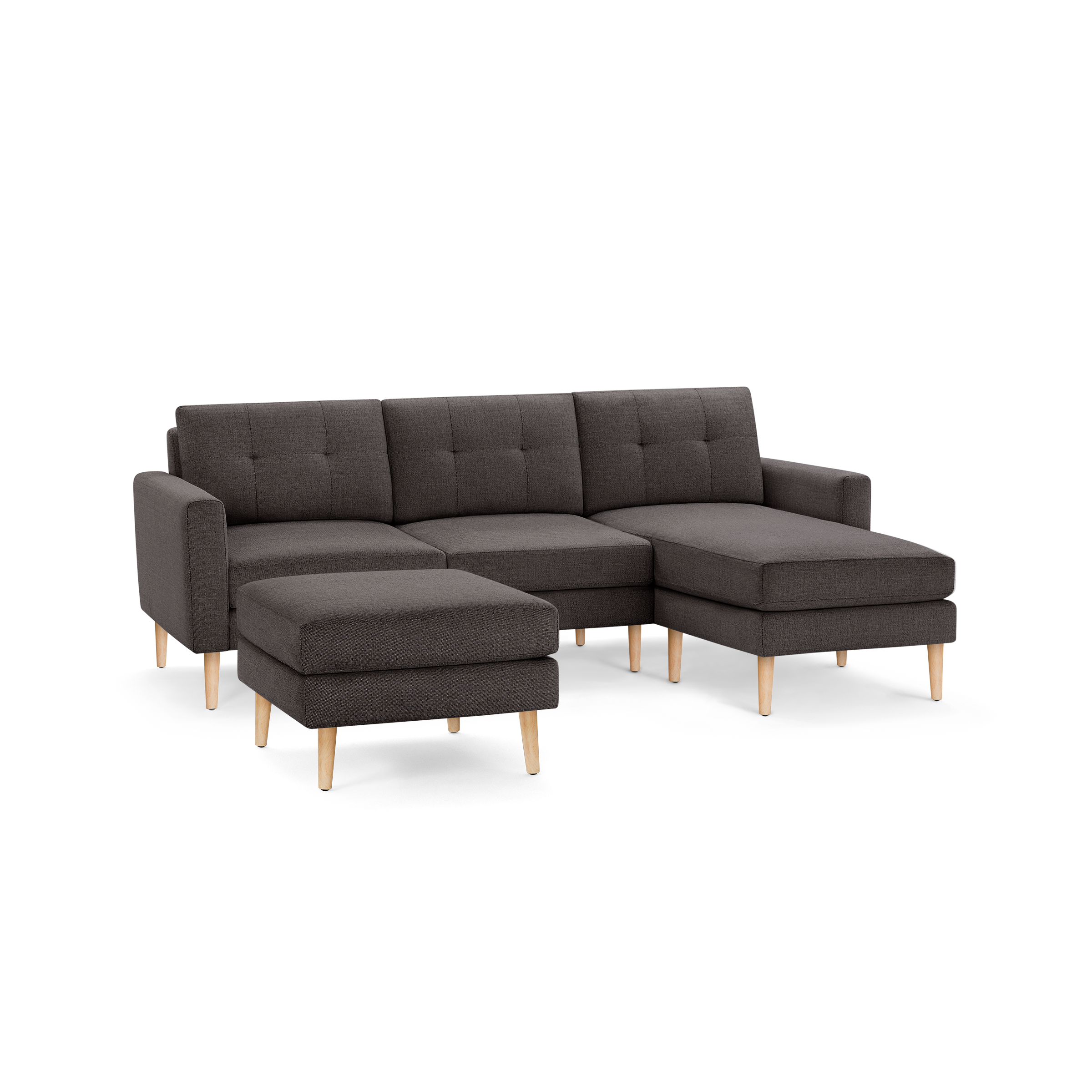 Modern dark gray fabric sectional sofa with tufted cushions, wooden legs, and matching ottoman on a black background.