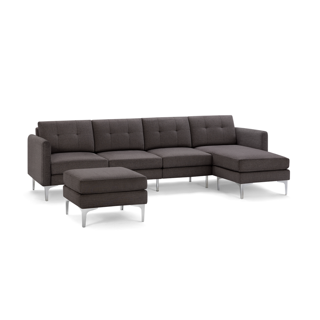 Dark gray L-shaped sectional sofa with tufted cushions and matching ottoman, featuring sleek metal legs.