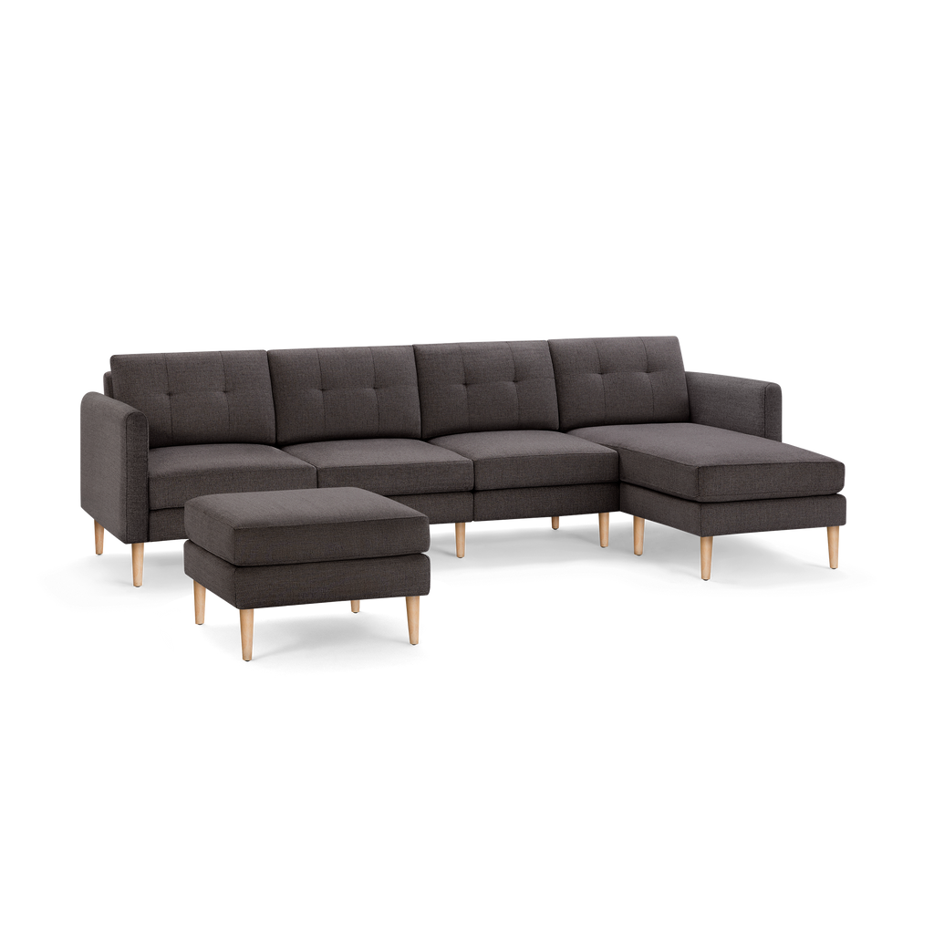 Dark gray fabric sectional sofa with tufted back cushions, wooden legs, and a matching ottoman on a black background.