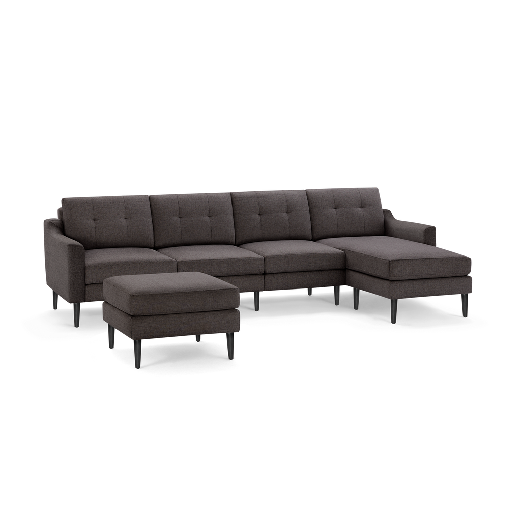 Dark gray fabric sectional sofa with tufted back cushions, slim black legs, and a matching ottoman.
