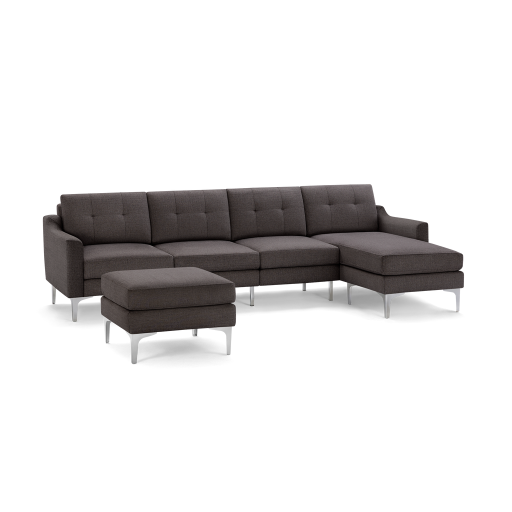 Modern dark gray fabric sectional sofa with tufted cushions, metal legs, and matching ottoman on black background.