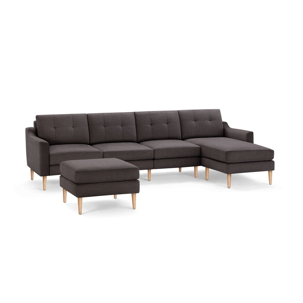 Modern dark gray fabric sectional sofa with tufted cushions, wooden legs, and a matching removable ottoman.