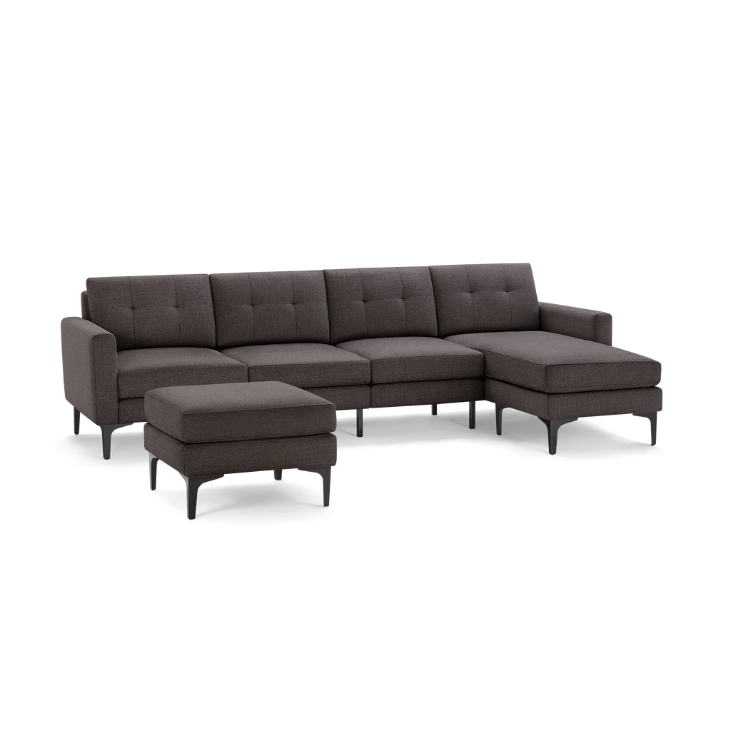 Dark gray modern sectional sofa with tufted cushions, left armrest, chaise lounge on right, and matching ottoman, supported by black legs.