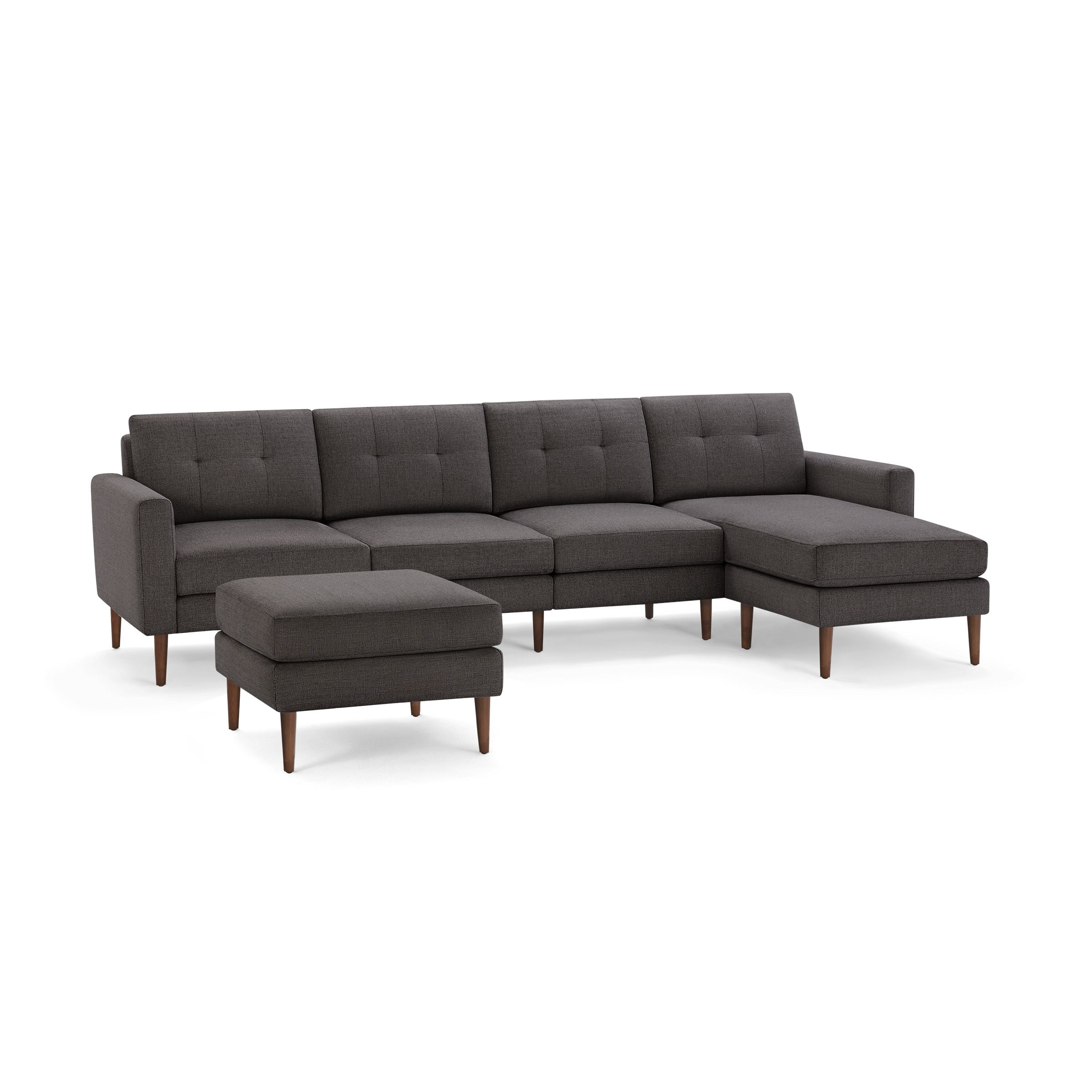 Dark gray fabric sectional sofa with tufted cushions, wooden legs, and matching ottoman on a black background.