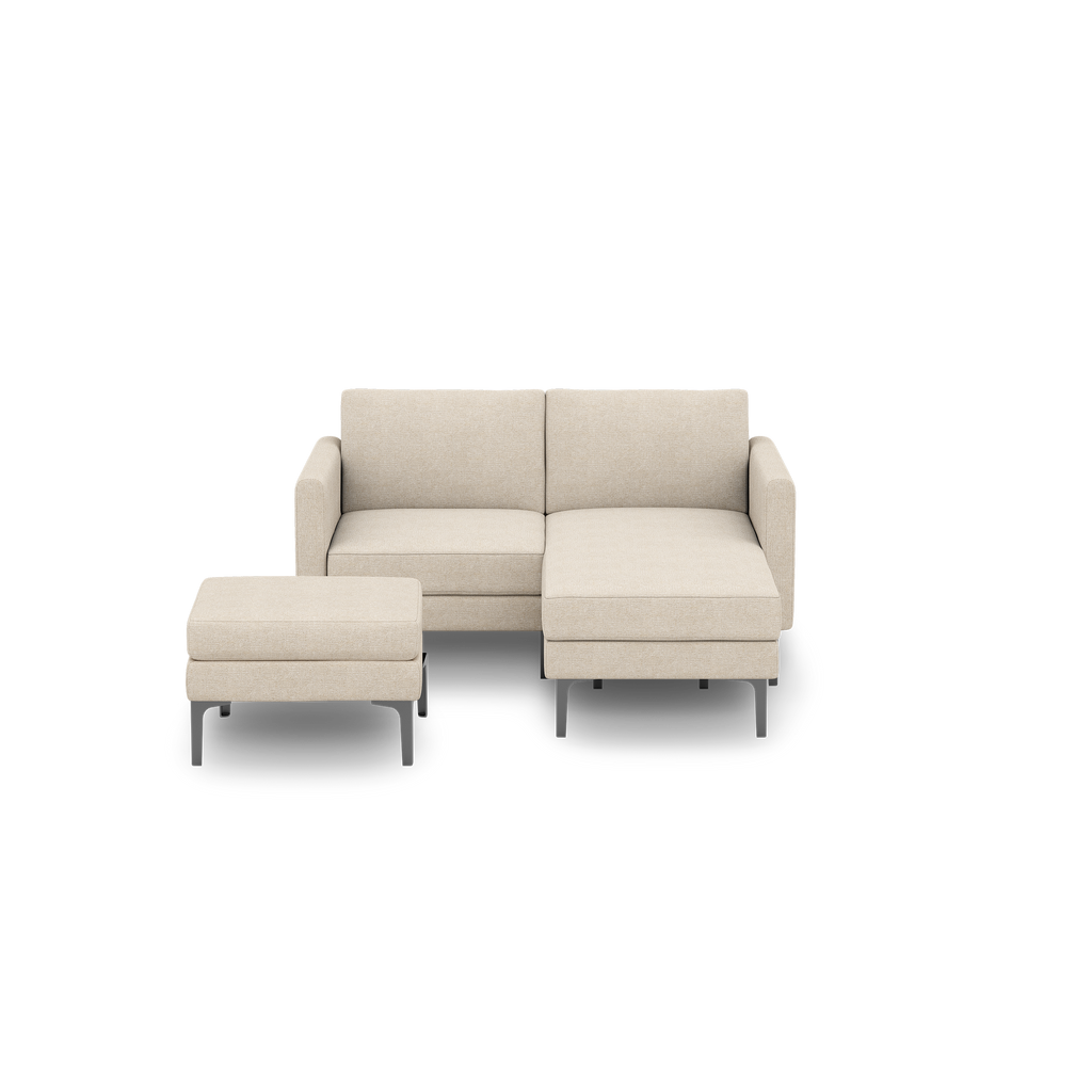 Beige fabric sectional sofa with a chaise lounge on the right and a matching ottoman with gray metal legs.