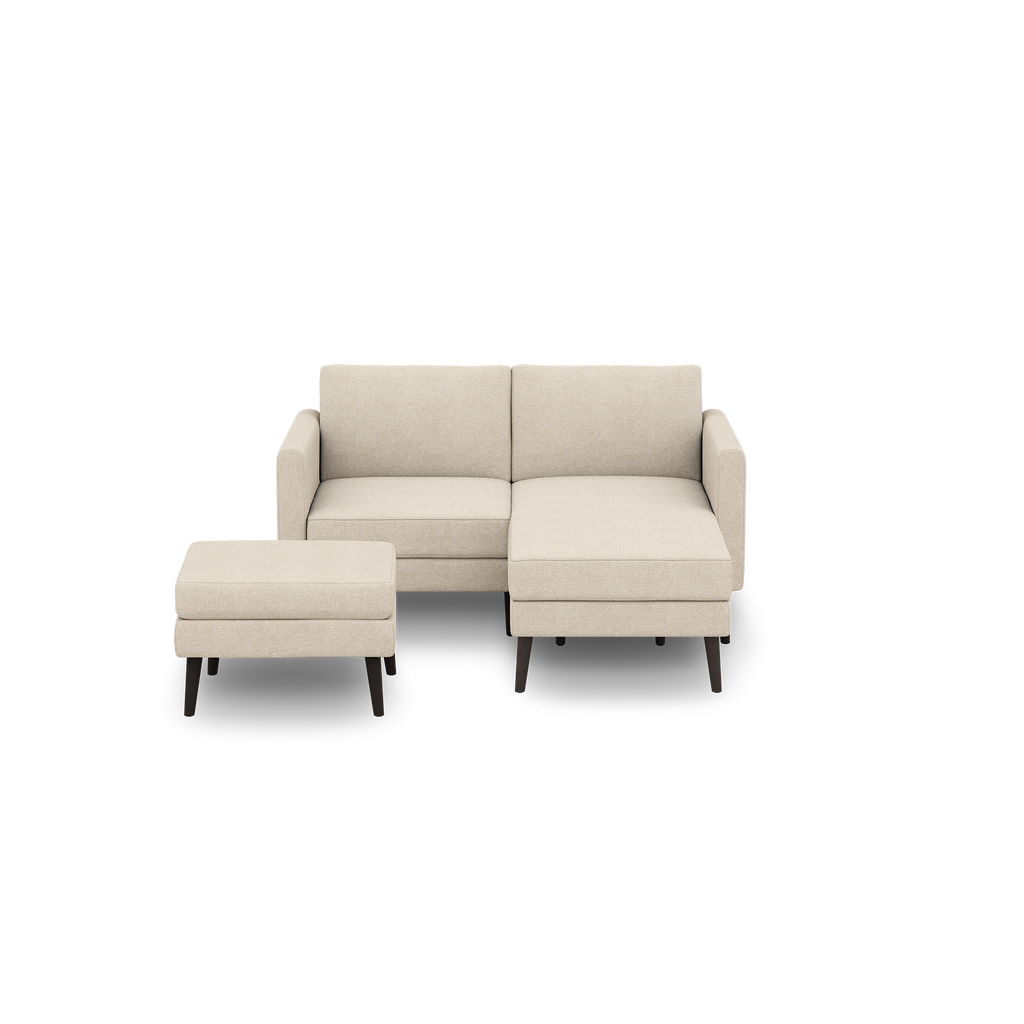 Beige modern sectional sofa with a matching ottoman, featuring clean lines and dark wooden legs, displayed on a black background.