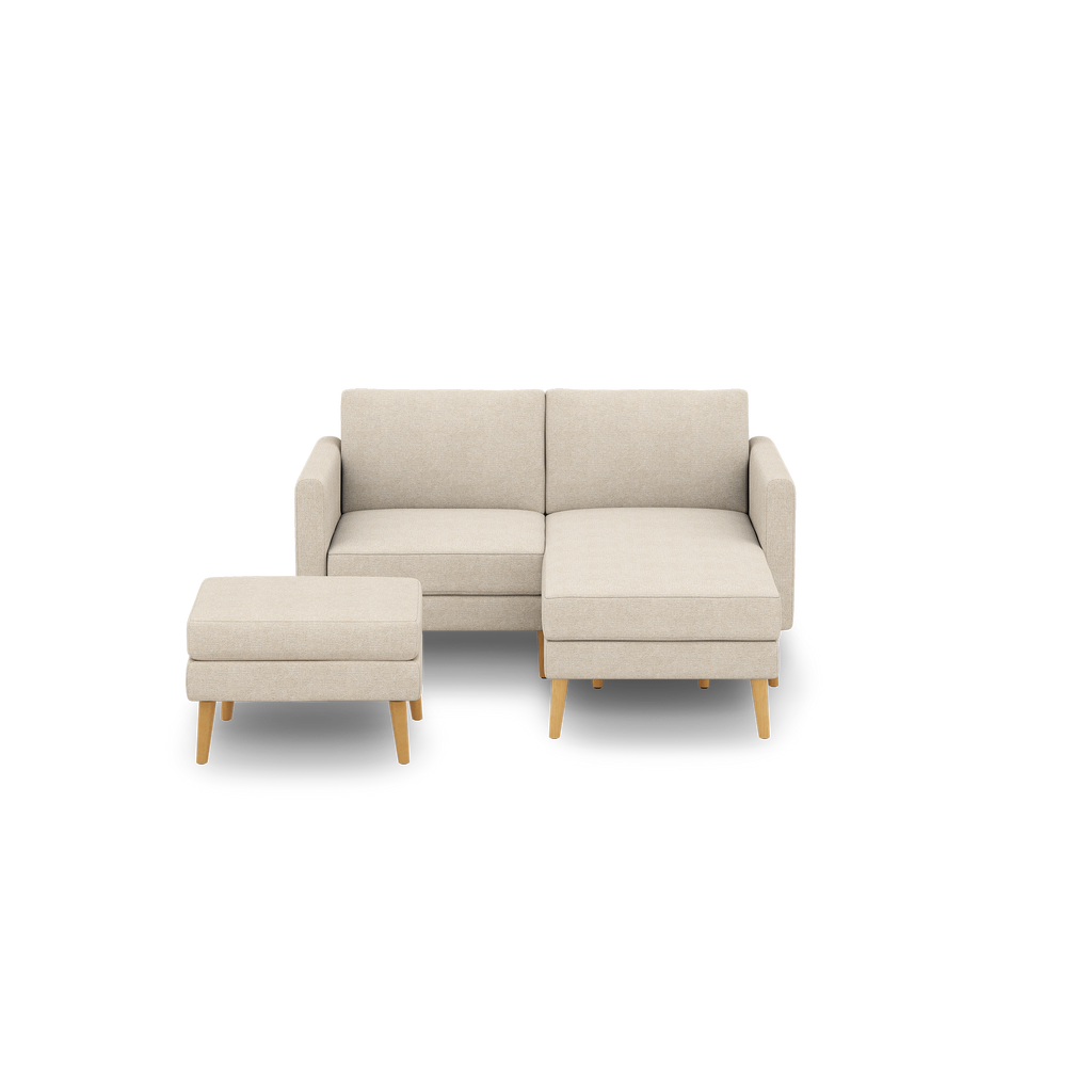 Beige two-seater sectional sofa with matching ottoman, featuring wooden legs and fabric upholstery against black background.