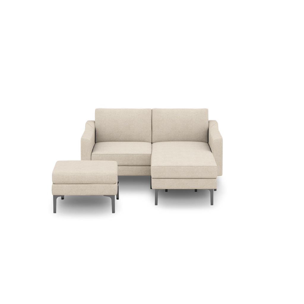 Beige fabric sectional sofa with chaise lounge and matching ottoman, modern design with metal legs, isolated on black background.