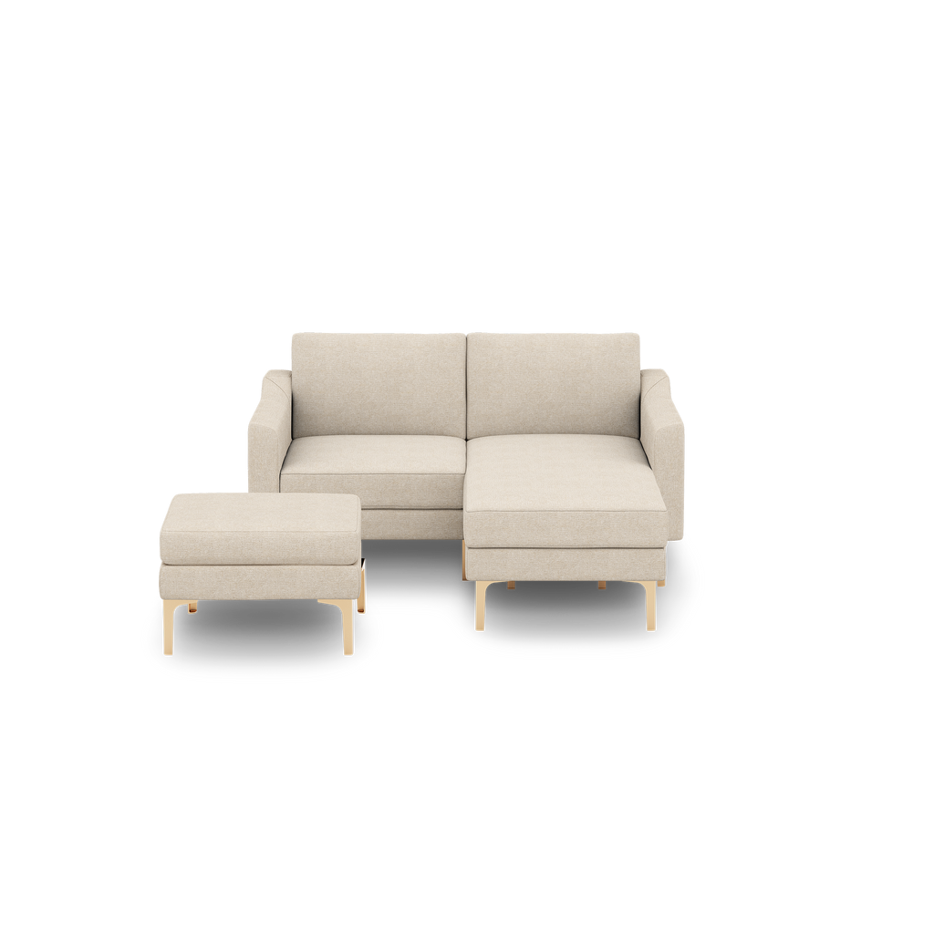 Beige modern sectional sofa with wooden legs, including a chaise lounge on the right and a matching ottoman on the left.