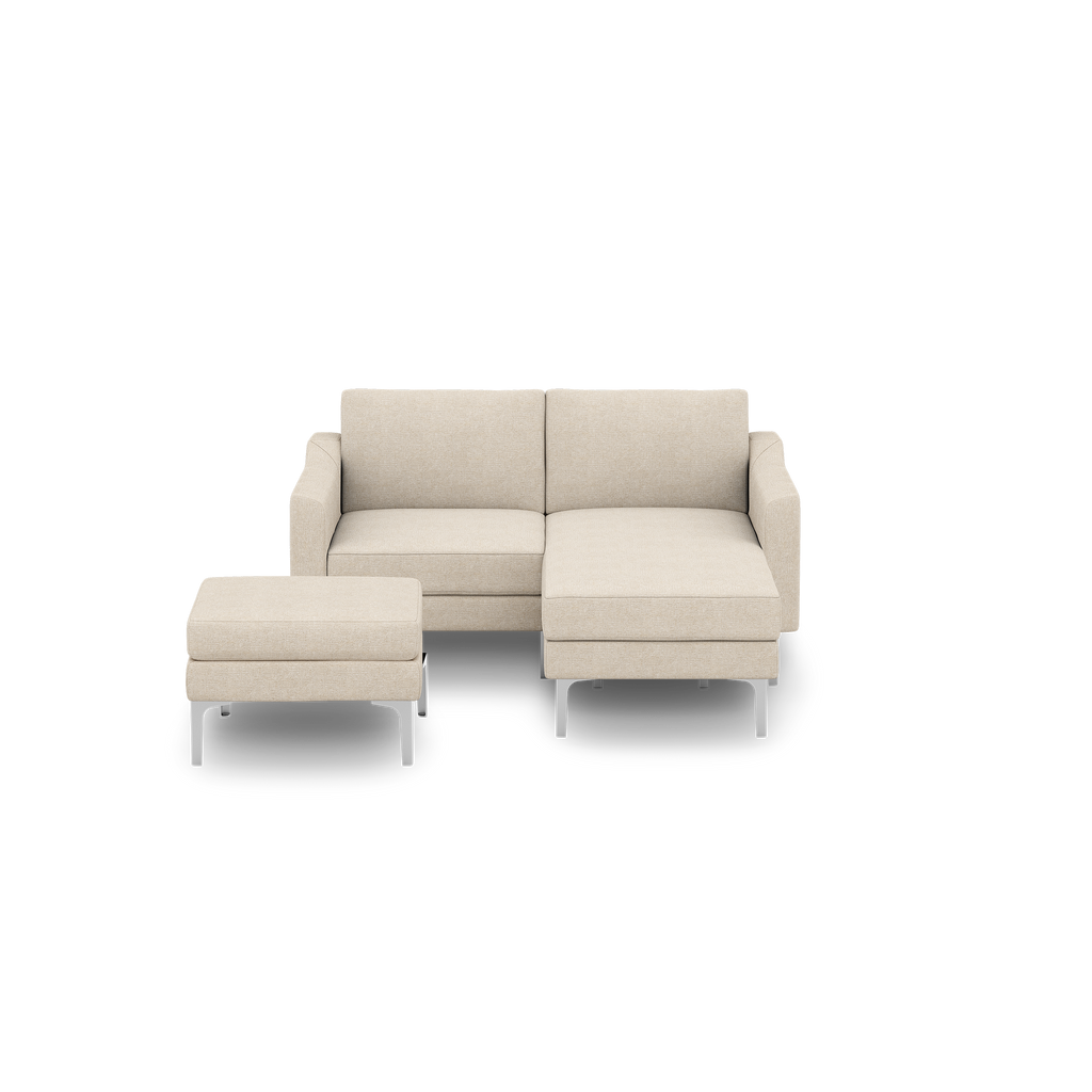 Beige modern sectional sofa with chaise lounge and matching ottoman, featuring slim metal legs and clean lines, isolated on black background.