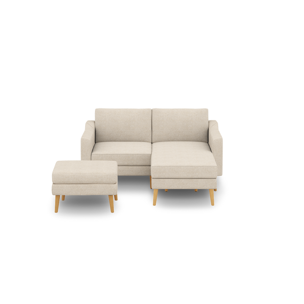 Beige two-seater sofa with attached chaise lounge and matching ottoman, featuring wooden tapered legs and clean, modern design.