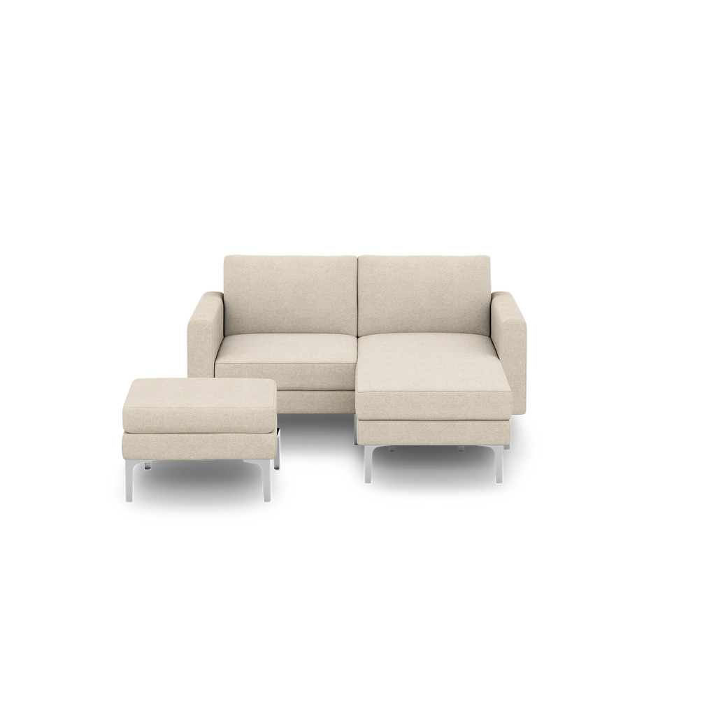 Beige fabric loveseat sectional sofa with chaise lounge and matching ottoman, featuring modern silver metal legs on a black background.