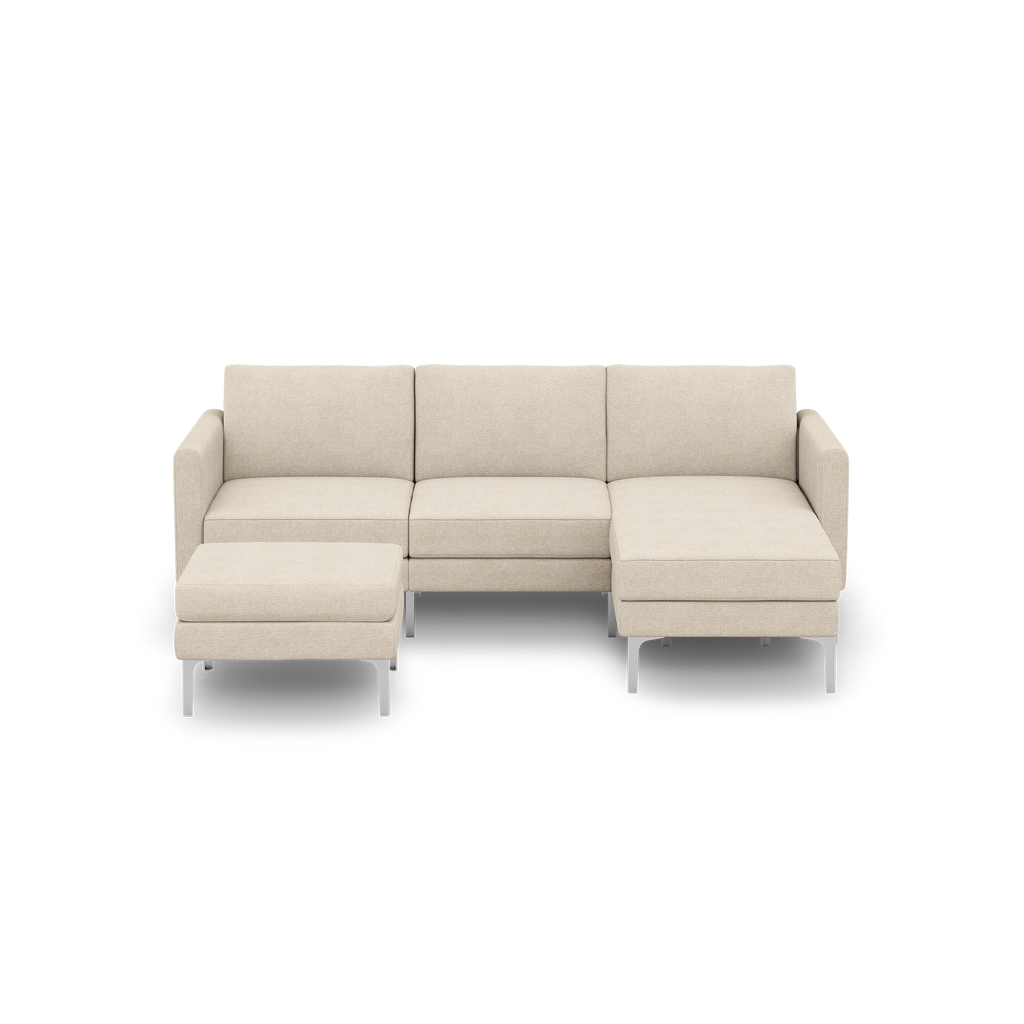 Beige modern sectional sofa with three seat cushions, a chaise lounge on the right, and a matching ottoman on metal legs.