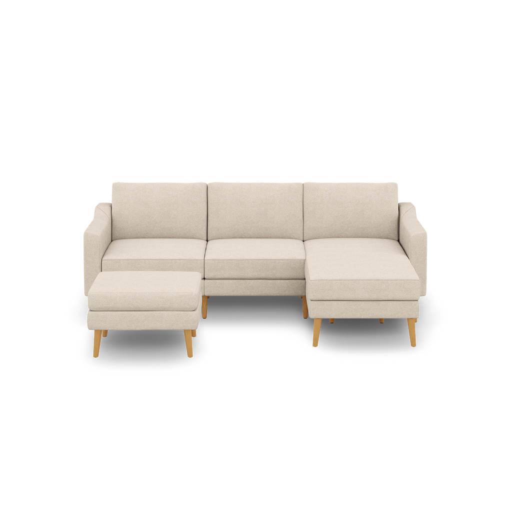 Beige sectional sofa with wooden legs, featuring three-seat cushions and a matching ottoman, modern and minimalist design.
