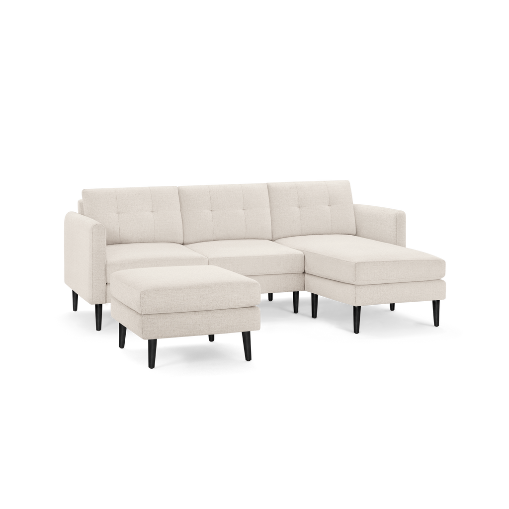 Beige fabric sectional sofa with tufted back cushions, right chaise lounge, and separate ottoman on black tapered legs.