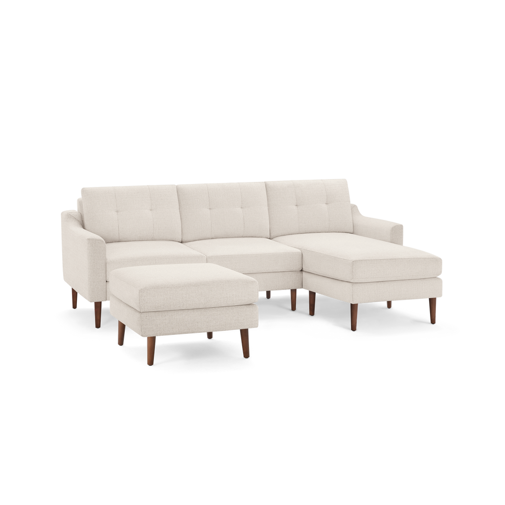 Beige L-shaped sectional sofa with tufted back cushions and wooden legs, including a matching ottoman.