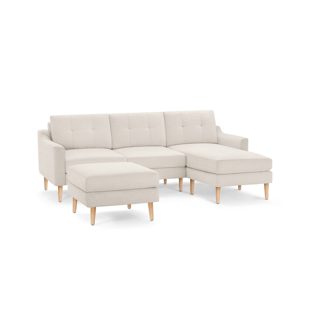 Beige fabric sectional sofa with tufted back cushions, wooden legs, and a matching ottoman, designed for modern living spaces.