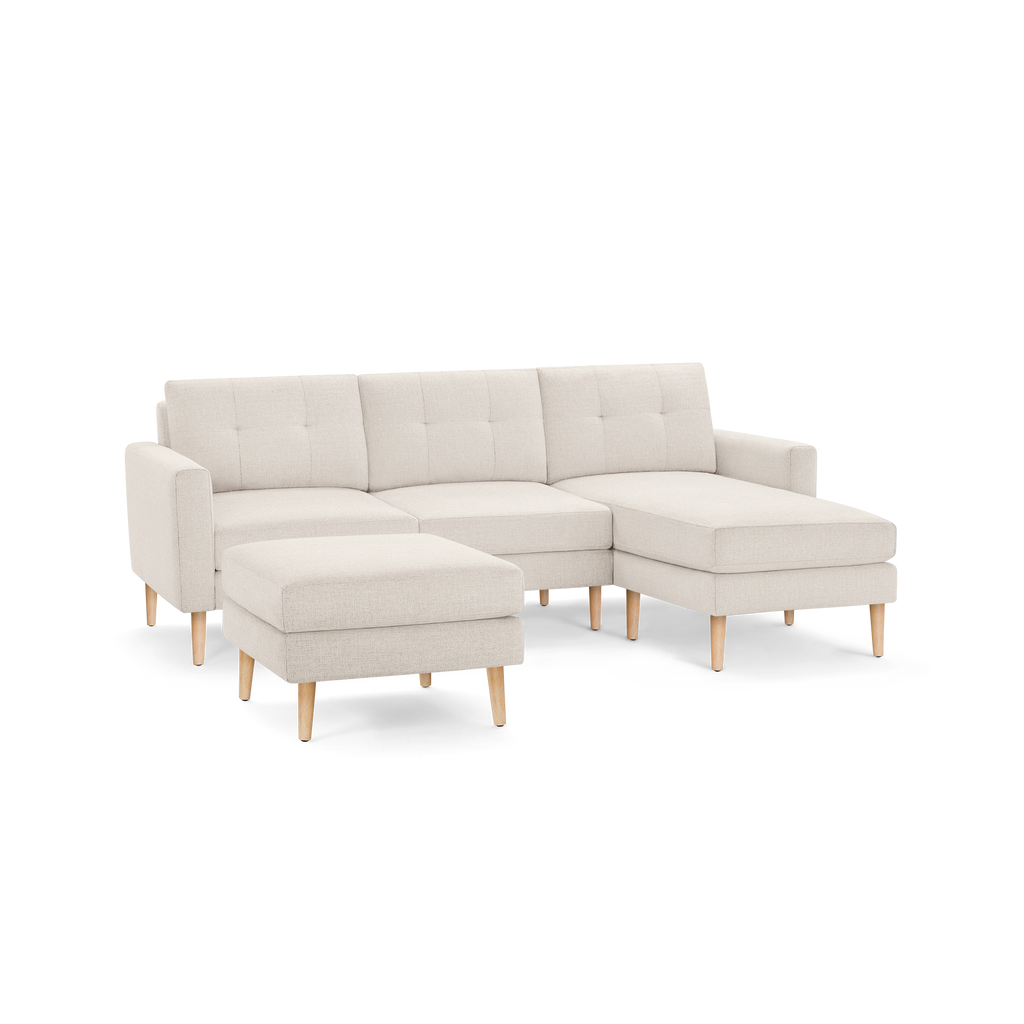 Beige modern sectional sofa with tufted cushions, wooden legs, and matching ottoman, offering comfortable seating and chaise lounge.