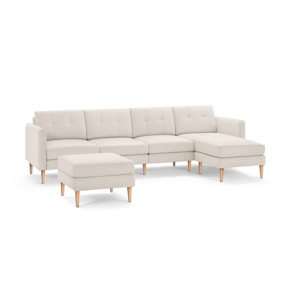 Beige modern sectional sofa with tufted cushions, wooden legs, matching ottoman, and chaise lounge on the right side.