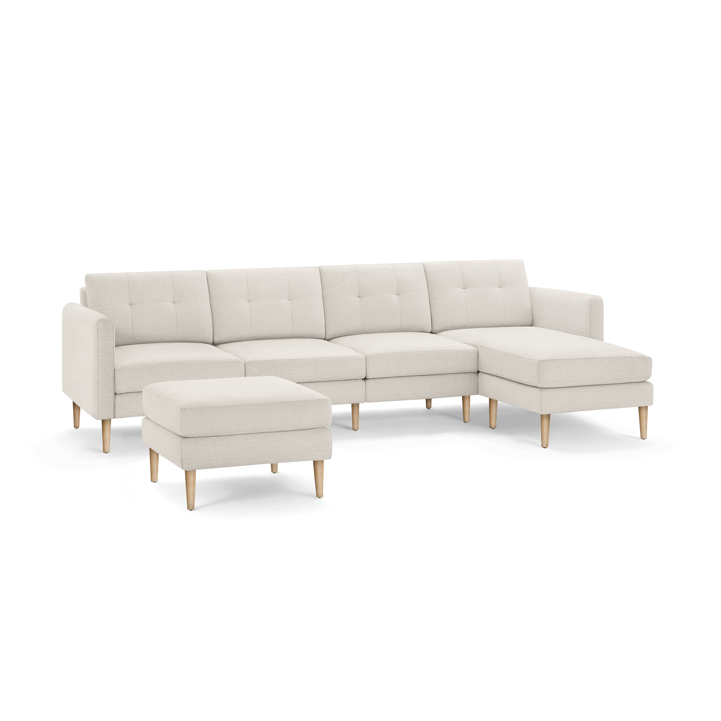 Beige modern sectional sofa with tufted cushions, wooden legs, matching ottoman, and chaise lounge on the right side.