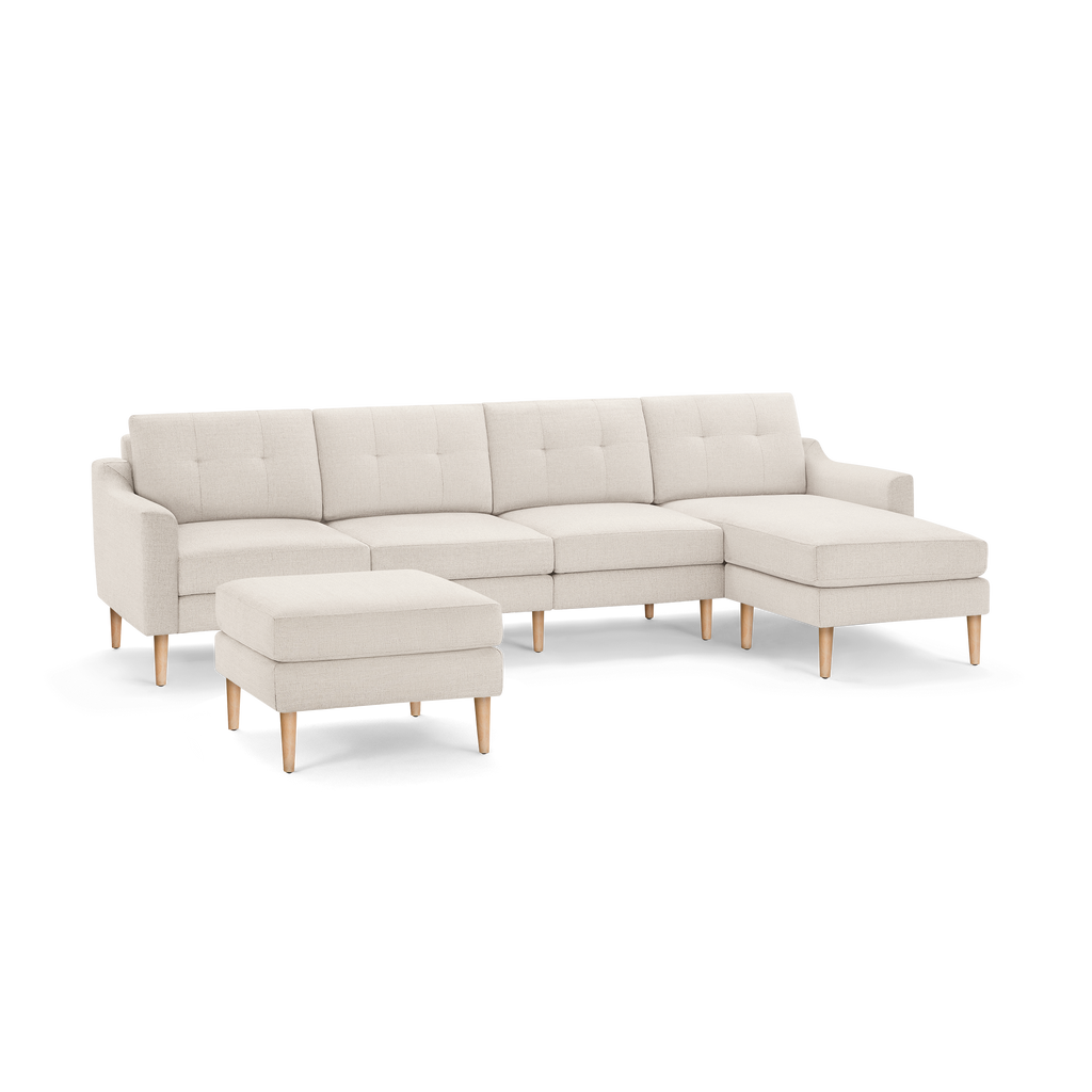Cream-colored modern sectional sofa with tufted back cushions, wooden legs, and matching ottoman on black background.