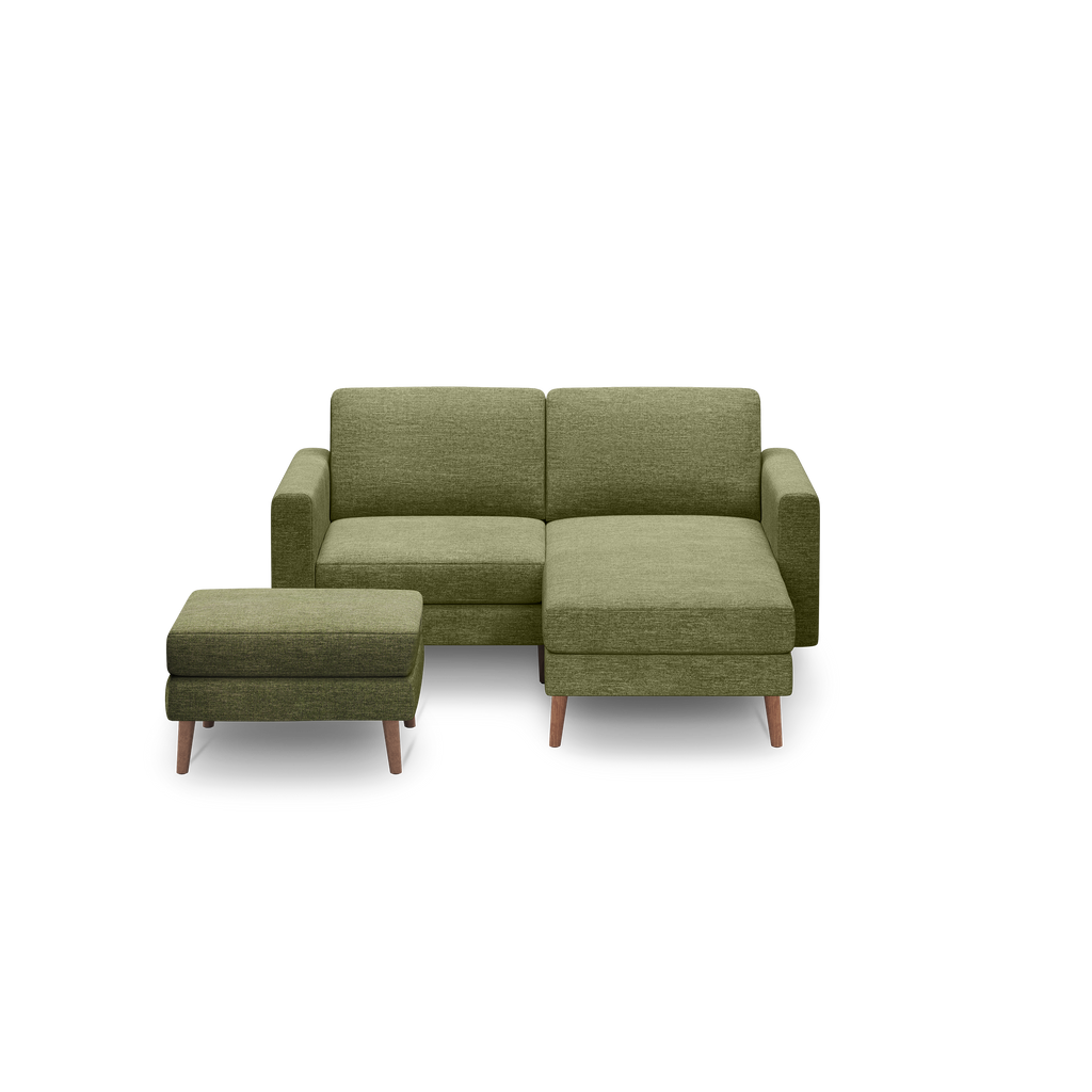 Green upholstered sectional sofa with chaise lounge and matching ottoman, featuring wooden legs, modern minimalist design.